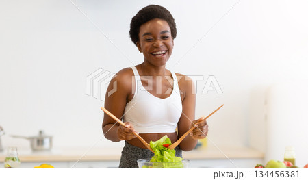 Healthy Diet. African Lady Cooking Salad Slimming At Home, Posing Wearing Fitwear Standing In Modern Kitchen Indoors, Smiling To Camera. Weight Loss Nutrition And Dieting Concept 134456381