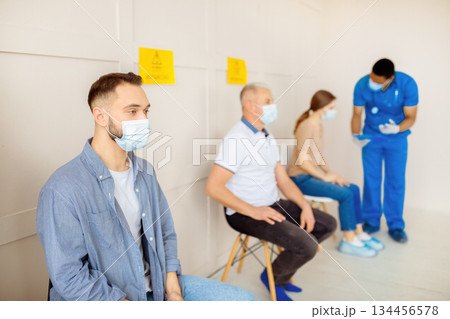 Young Caucasian man waiting in line for covid-19 vaccine injection at clinic. Millennial guy participating in coronavirus immunization campaign at health centre. Medical care and health services 134456578