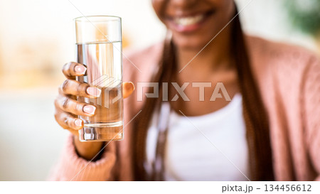 Unrecognizable Black Woman Offering Glass Of Water To Camera, Positive Young African American Female Recommending Healthy Refreshing Drink For Body Hydration, Closeup Shot, Cropped Image 134456612