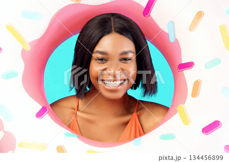 Portrait of cheerful young black lady in swimsuit posing with donut shaped inflatable ring, smiling at camera over blue studio background. African American woman having fun beach vacation in summer 134456899