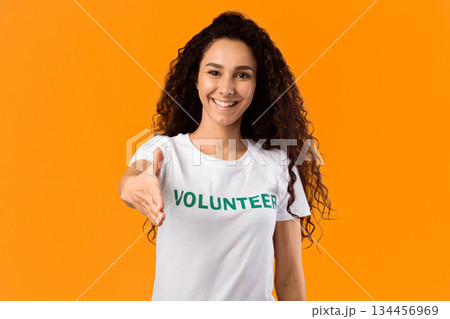 Cheerful Volunteer Woman Offering Hand For Handshake Greeting To Camera Posing Standing Over Yellow Studio Background. Volunteering, Voluntary Work, Join Our Team Concept Cheerful Volunteer Woman Offering Hand For Handshake Greeting To Camera Posing Standing Over Yellow Studio Background. Volunteering, Voluntary Work, Join Our Team Concept 134456969