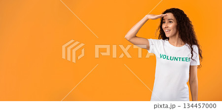 Female Volunteer Looking Aside At Free Space For Advertisement Text Holding Hand Near Eyes Posing Standing Over Yellow Studio Background. Activist Advertising Volunteering Project Female Volunteer Looking Aside At Free Space For Advertisement Text Holding Hand Near Eyes Posing Standing Over Yellow Studio Background. Activist Advertising Volunteering Project 134457000
