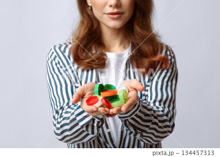 Unrecognizable Lady Holding Colorful Plastic Lids Bottle Cups In Hands. Eco-Friendly Woman Enjoying Waste Sorting And Garbage Recycling Living, Standing Over Gray Background, Cropped Image, Closeup Unrecognizable Lady Holding Colorful Plastic Lids Bottle Cups In Hands. Eco-Friendly Woman Enjoying Waste Sorting And Garbage Recycling Living, Standing Over Gray Background, Cropped Image, Closeup 134457313