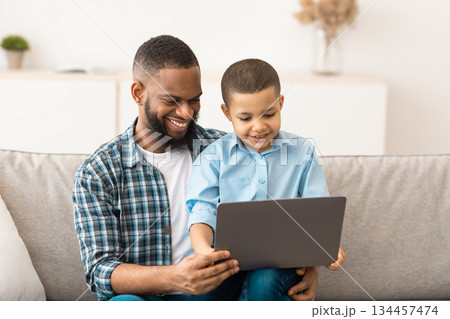 Little Boy Watching Movie On Tablet Sitting On Dad's Knees, Using Computer Together And Browsing Internet At Home. Gadgets, Weekend Family Leisure Concept Little Boy Watching Movie On Tablet Sitting On Dad's Knees, Using Computer Together And Browsing Internet At Home. Gadgets, Weekend Family Leisure Concept 134457474