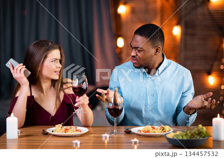 Annoyed Black Guy Arguing With His Girlfriend Busy With Cellphone On Date In Restaurant. Young Multiracial Couple Having Problems In Relationship During Romantic Dinner At Valentine's Day, Free Space Annoyed Black Guy Arguing With His Girlfriend Busy With Cellphone On Date In Restaurant. Young Multiracial Couple Having Problems In Relationship During Romantic Dinner At Valentine's Day, Free Space 134457532
