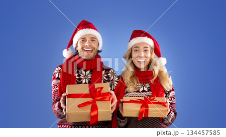 Christmas shopping. Portrait of happy couple with Xmas gifts on blue background 134457585