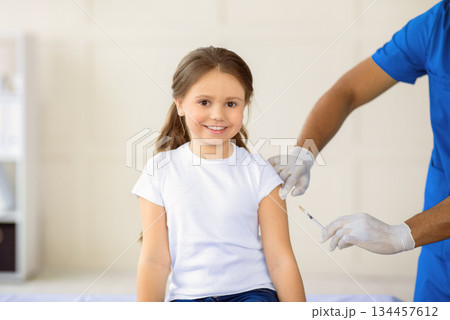 African American doctor making coronavirus vaccine injection to little girl at clinic, panorama. Positive child receiving covid-19 immunization at hospital. Protection against virus concept African American doctor making coronavirus vaccine injection to little girl at clinic, panorama. Positive child receiving covid-19 immunization at hospital. Protection against virus concept 134457612