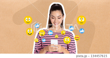In a casual setting, a woman with long hair smiles as she chats on her smartphone. Colorful emojis surround her, reflecting her joyful interaction on social media and messaging. 134457615