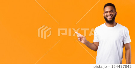 Black Man Pointing Finger Aside Advertising Your Text Standing Posing Smiling To Camera Over Yellow Studio Background. Look There, Advertisement Banner Concept. Empty Space For Text 134457843