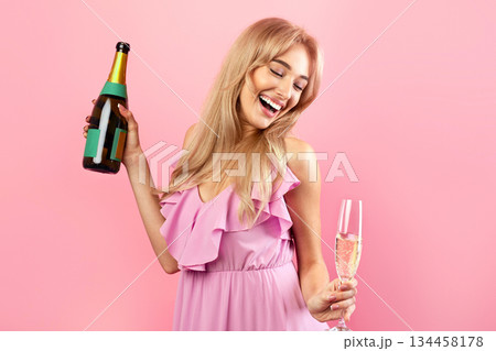 Cheerful millennial woman celebrating special occasion with bottle and glass of champagne over pink studio background, banner design with copy space. Beautiful lady partying with alcoholic drink Cheerful millennial woman celebrating special occasion with bottle and glass of champagne over pink studio background, banner design with copy space. Beautiful lady partying with alcoholic drink 134458178