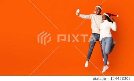 Joyful Black Couple Taking Selfie On Smartphone, Having Fun On Christmas Holidays, Jumping And Posing On Orange Studio Background, Enjoying Celebrating Xmas Together, Full Length Shot, Copy Space Joyful Black Couple Taking Selfie On Smartphone, Having Fun On Christmas Holidays, Jumping And Posing On Orange Studio Background, Enjoying Celebrating Xmas Together, Full Length Shot, Copy Space 134458305