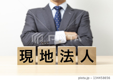 「現地法人」と書かれたブロックと腕組みをするビジネスマン 「現地法人」と書かれたブロックと腕組みをするビジネスマン 134458656