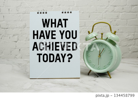 What Have You Achieved Today? with green vintage alarm clock against a white brick wall background. 134458799