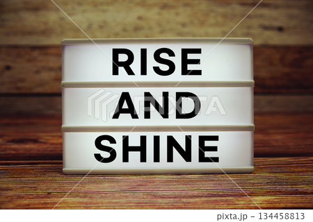 Lightbox with text "Rise And Shine" on wooden background 134458813