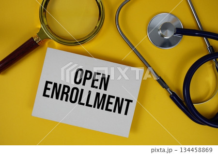 Open Enrollment text on paper card with Stethoscope flat lay on yellow background 134458869