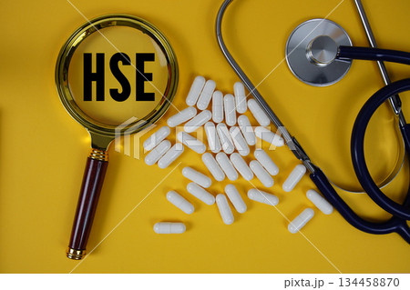 HSE Health Safety Environment text with magnifying glass and Stethoscope on yellow background 134458870