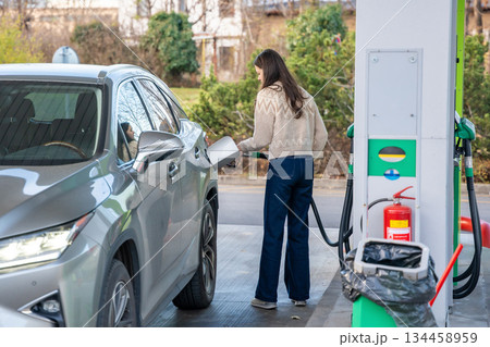 Woman refueling her car at a self-service gas station. Urban mobility and daily routine. Woman refueling her car at a self-service gas station. Urban mobility and daily routine. 134458959