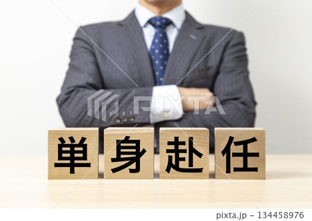 「単身赴任」と書かれたブロックと腕組みをするビジネスマン 134458976