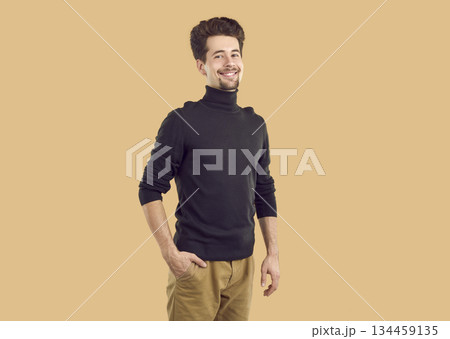 Portrait of happy confident brunet guy in black turtleneck on beige background looking at camera. Portrait of happy confident brunet guy in black turtleneck on beige background looking at camera. 134459135