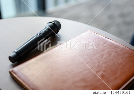マイクと手帳が置かれた会議室の机 134459161