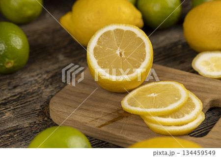 sliced yellow sour lemon lying on the table with green limes, sliced ripe citrus fruits lemon and limes are lying on a wooden table sliced yellow sour lemon lying on the table with green limes, sliced ripe citrus fruits lemon and limes are lying on a wooden table 134459549