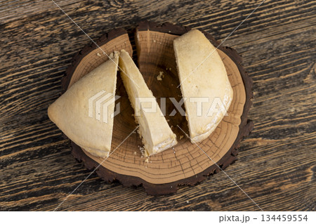 sliced fresh shortbread bun with juicy curd filling on a wooden board on the table, soft pastries stuffed with cottage cheese 134459554