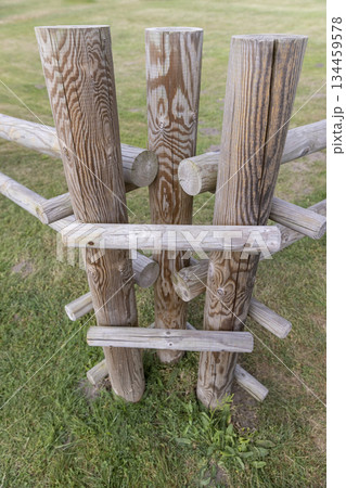 part of a wooden fence made of logs and roundwood in rural areas, primitive fencing against large animals in rural areas during the summer season, cloudy weather part of a wooden fence made of logs and roundwood in rural areas, primitive fencing against large animals in rural areas during the summer season, cloudy weather 134459578