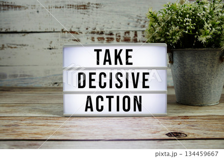 Take Decisive Action text on light box on wooden background 134459667