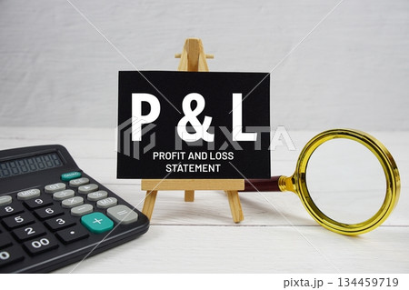 P and L abbreviation of Profit And Loss Statement text with magnifying glass and calculator on wooden background P and L abbreviation of Profit And Loss Statement text with magnifying glass and calculator on wooden background 134459719