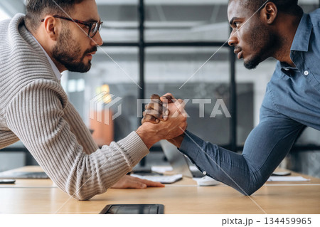 Two office workers are having fun and doing arm wrestling 134459965