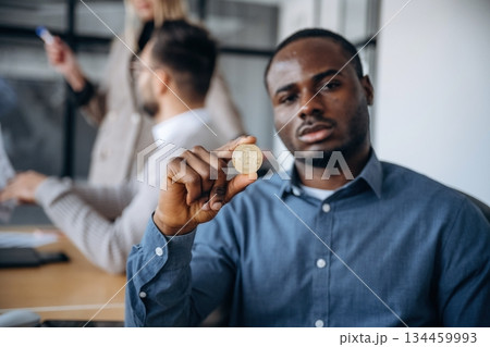 Crypto currency, coin in hand. Professional workers are in the modern office together 134459993