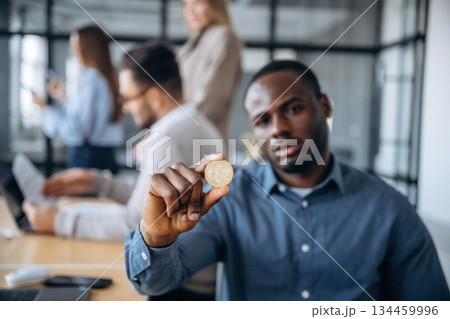 Crypto currency, coin in hand. Professional workers are in the modern office together 134459996