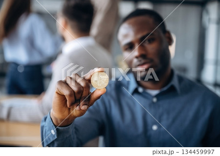 Crypto currency, coin in hand. Professional workers are in the modern office together Crypto currency, coin in hand. Professional workers are in the modern office together 134459997