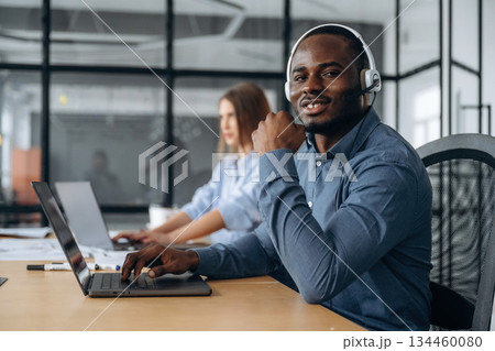 In headphones and with laptops. People are working in the call center In headphones and with laptops. People are working in the call center 134460080