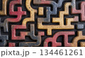 An intricate abstract maze design with interconnected shapes in black, red, yellow, and gray on a textured surface 134461261