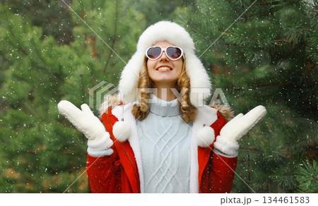 Winter portrait of happy smiling woman having fun enjoys snow against Christmas tree in forest Winter portrait of happy smiling woman having fun enjoys snow against Christmas tree in forest 134461583