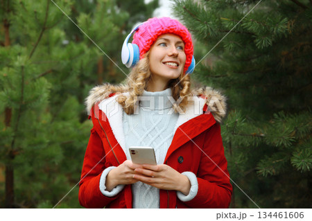 Happy young woman enjoy listening to music with headphones using phone in winter 134461606