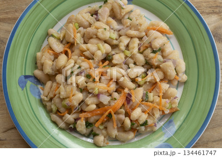 white bean salad with carrots and herbs on green plate close up 134461747