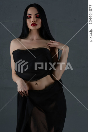Elegant woman modeling black lingerie with sheer fabric indoors 134464077