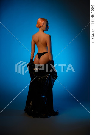 Woman in lingerie poses against a blue background with artistic lighting Woman in lingerie poses against a blue background with artistic lighting 134464084