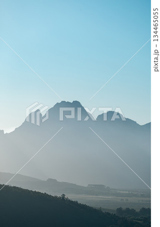 Misty mountain range under clear blue sky with soft light at sunrise 134465055