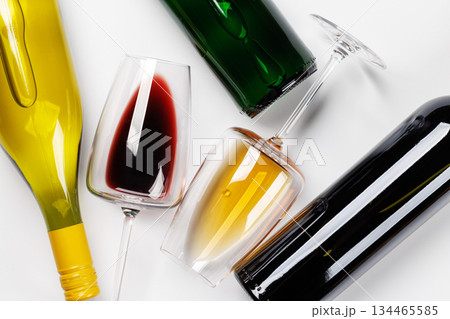 Wine glasses with red and white wine and bottles lying on white background 134465585