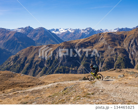 Scuol, Switzerland - October 11th 2025: A female cyclist riding her bike in motta-naluns resort with a fantastic view. Scuol, Switzerland - October 11th 2025: A female cyclist riding her bike in motta-naluns resort with a fantastic view. 134465825