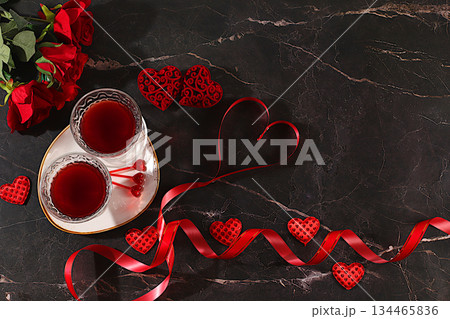 Two glasses of red wine on a festive table with roses, hearts, and a ribbon. Valentine's Day concept, advertising for a bar and cafe. Banner for an invitation to a festive buffet, card for a wedding 134465836
