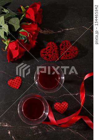 Two glasses of red wine on a festive table with roses, hearts, and a ribbon. Valentine's Day concept, advertising for a bar and cafe. Banner for an invitation to a festive buffet, card for a wedding, 134465842