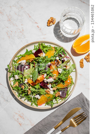 A fresh salad of beets, orange, and arugula with feta, walnuts, and balsamic dressing on a plate 134465862