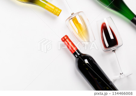 Wine glasses with red and white wine and bottles lying on white background Wine glasses with red and white wine and bottles lying on white background 134466008