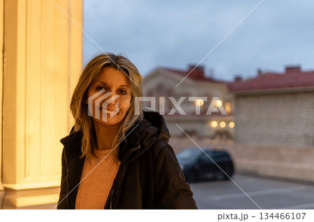 Woman portrait city lights confident middle aged female smiling happily standing outdoors urban street at dusk 134466107
