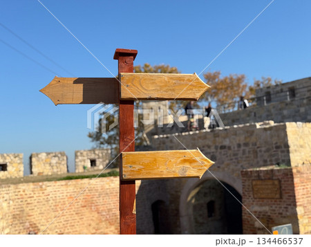 Wooden signpost in historic fortress. Choice, exploration and human journey through time and direction. Wooden signpost in historic fortress. Choice, exploration and human journey through time and direction. 134466537