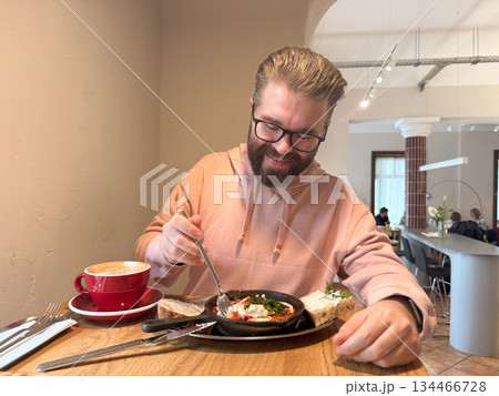 Man dining alone in cafe with breakfast. Morning calm, slow living and appreciation of simple comfort through food and space. Man dining alone in cafe with breakfast. Morning calm, slow living and appreciation of simple comfort through food and space. 134466728